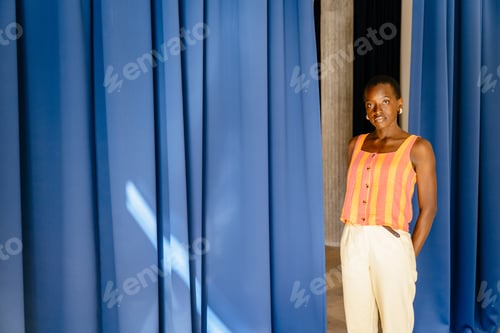 Preview: Neutral Black woman in blue curtain space with bold orange color contrast