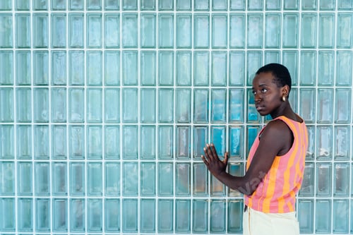 Preview: Neutral Black woman standing in minimalist interior with glass block wall