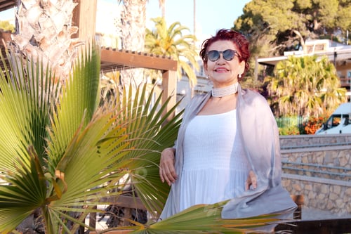 Preview: An elderly woman wearing sunglasses strolls and enjoys the beautiful view of a tropical seaside reso