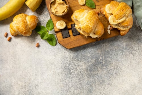 Preview: French pastry, freshly baked croissants with peanut butter and banana on a grey stone background. He