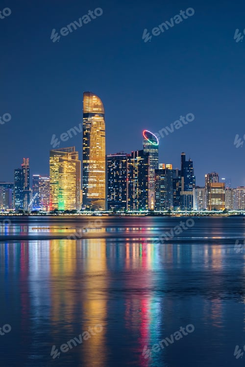 Preview: Abu Dhabi skyline at night with illuminated towers and colorful reflections