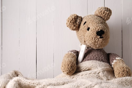 Preview: Toy bear with thermometer under blanket near white wooden wall, space for text