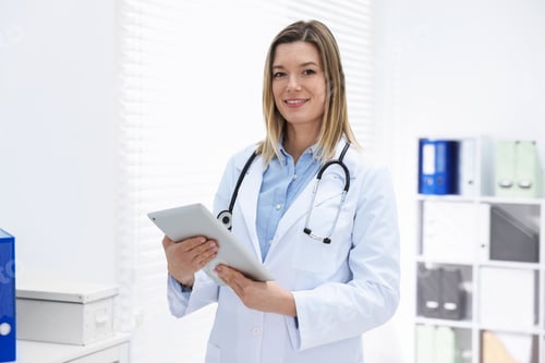 Preview: Portrait of smiling doctor in medical coat with tablet and stethoscope in clinic
