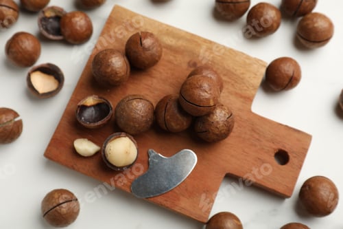 Preview: Macadamia nuts and metal key on white table, flat lay