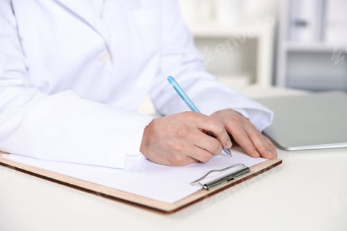 Preview: Doctor writing in clipboard at table indoors, closeup