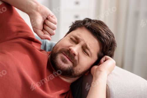 Preview: Unhappy man feeling fatigue on sofa at home