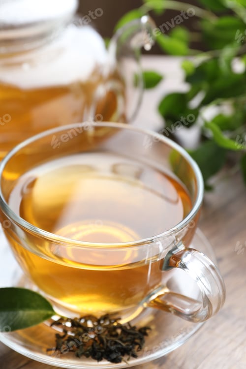 Preview: Refreshing green tea and dry leaves on wooden table, closeup