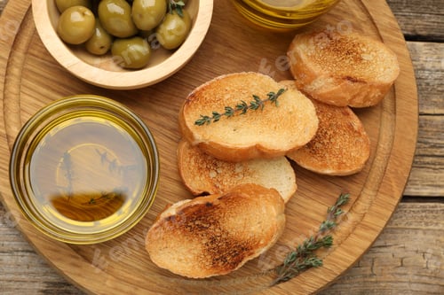 Preview: Slices of baguette, oil, olives and thyme on wooden table, top view