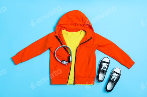 Preview: Flat lay composition with stylish child clothes, shoes and headphones on light blue background