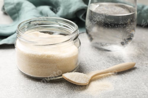 Preview: Gelatin powder and glass of water on light grey table, closeup