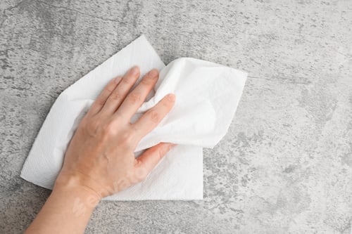 Vista previa: Woman wiping grey textured surface with paper towel, top view. Space for text