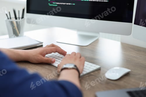 Preview: Programmer working with computer at desk in office, closeup