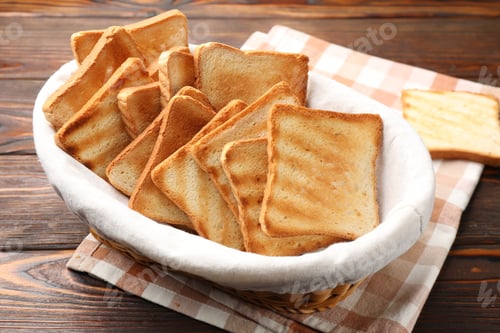 Preview: Browned toast bread slices in wicker basket on wooden table, closeup