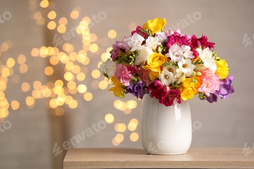 Preview: Beautiful freesia flowers in vase on wooden table indoors, space for text. Bokeh effect