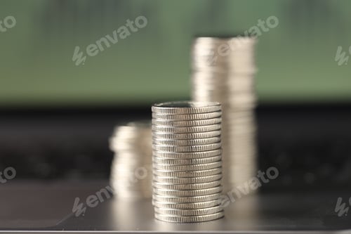 Preview: Stacks of coins on laptop against blurred background, closeup