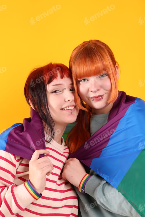 Preview: Lovely lesbian couple with rainbow flag on yellow background. LGBT concept