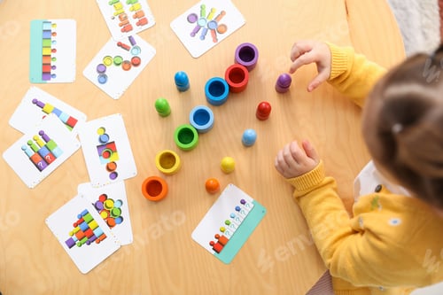 Vista previa: Cute little girl playing with toys at wooden table indoors, above view