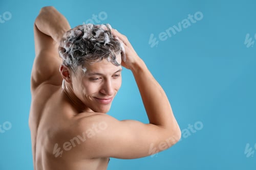 Preview: Man washing his hair with shampoo on light blue background, space for text