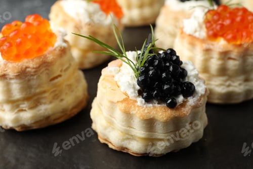 Preview: Tasty puff pastries with cream cheese, caviar and dill on black slate board, closeup