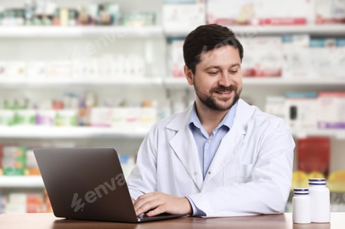 Preview: Pharmacist using laptop at table in drugstore
