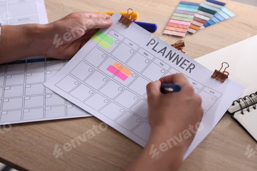 Preview: Man using planner at wooden table, closeup