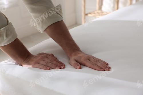 Preview: Man touching soft mattress on bed indoors, closeup