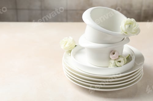 Preview: Clean dishware and beautiful flowers on light table. Space for text