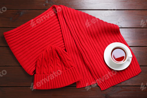 Preview: Knitted scarf, hat and tea on wooden table, top view