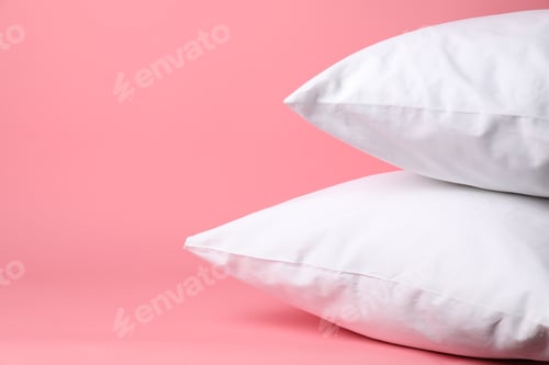 Preview: Bed linens. Pillows in clean pillowcases on pink background, closeup. Space for text
