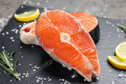 Preview: Pieces of salmon fillet with spices and lemon on table, closeup