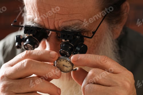 Preview: Senior man fixing mechanism of vintage wrist watch indoors, closeup