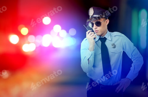 Preview: Young policeman in uniform outdoors. Toned in red and blue police lights