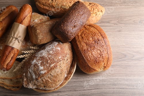 Preview: Different types of bread and spikes on wooden table, flat lay. Space for text