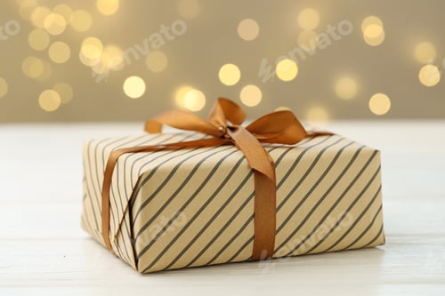 Preview: Beautifully wrapped gift on white wooden table against blurred lights, closeup