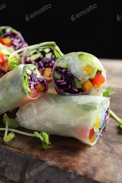 Preview: Delicious spring rolls wrapped in rice paper on wooden board, closeup