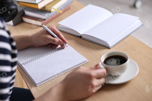 Preview: Student preparing for exam with cup of coffee at wooden desk, closeup