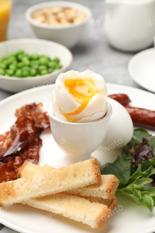 Preview: Tasty breakfast with soft boiled eggs and bacon served on grey table, closeup