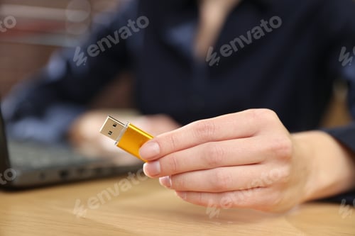 Preview: Woman with USB flash drive at wooden desk, closeup