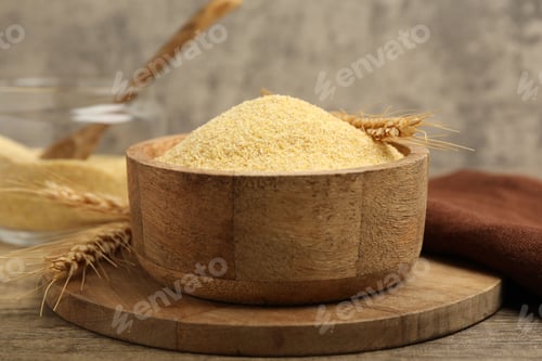 Preview: Raw semolina in bowl with spikes on wooden table, closeup