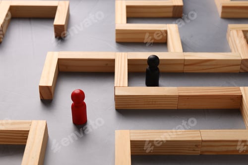 Preview: Maze made of wooden blocks and human figures on grey table, closeup. Business strategy