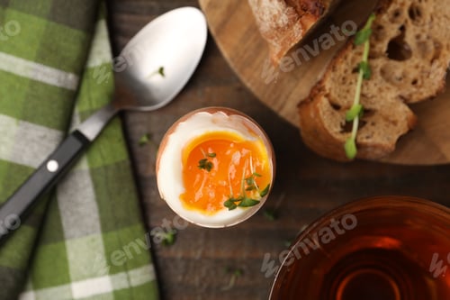 Preview: Tasty breakfast with soft boiled egg, microgreens, bread and tea on wooden table, flat lay