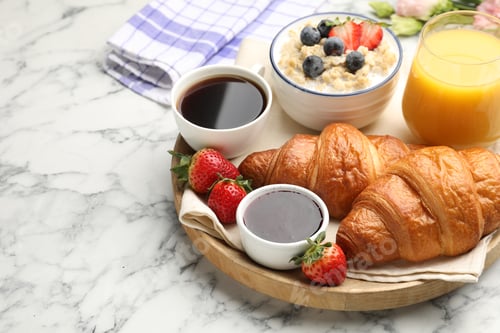 Preview: Healthy breakfast. Tasty croissants, jam, oatmeal with berries, orange juice and coffee on white mar