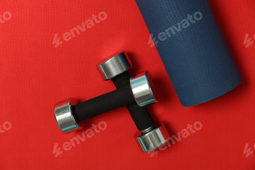 Preview: Dumbbells and fitness mat on red background, flat lay