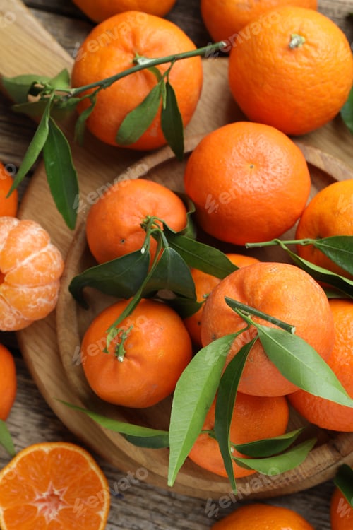 Preview: Fresh tangerines and green leaves on wooden table, flat lay