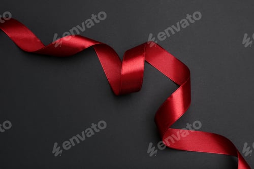 Preview: Beautiful red ribbon on dark background, top view
