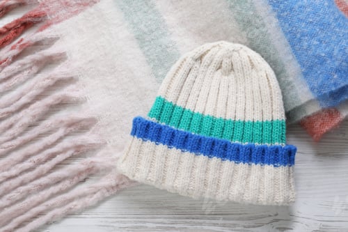 Preview: Soft scarf and knitted hat on wooden table, top view