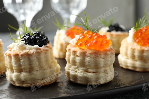 Preview: Tasty puff pastries with cream cheese, caviar and dill on black slate board, closeup