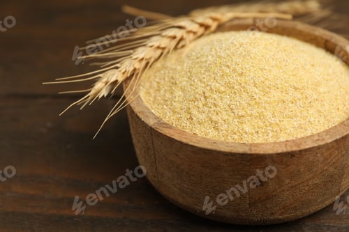 Preview: Raw semolina in bowl and spike on wooden table, closeup