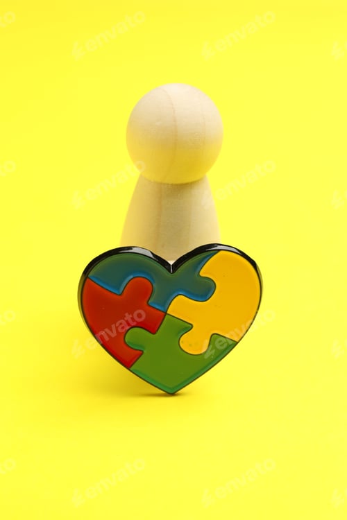 Preview: Autism. Human figure and heart made of puzzle pieces on yellow background, closeup