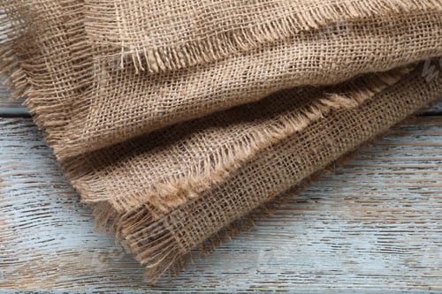 Preview: Natural burlap fabric on wooden table, top view